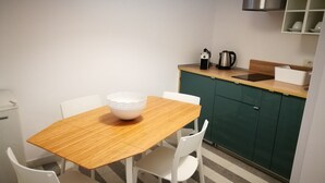 A small kitchen with a wooden table and white chairs, a kettle, and a coffee maker on the counter. - Simply House in Bari 2 (Bari)