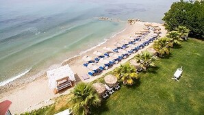 A beachside hotel with rows of blue umbrellas, a pool area, and a view of the ocean. - Nefeli Luxury Villas (Kassandra)