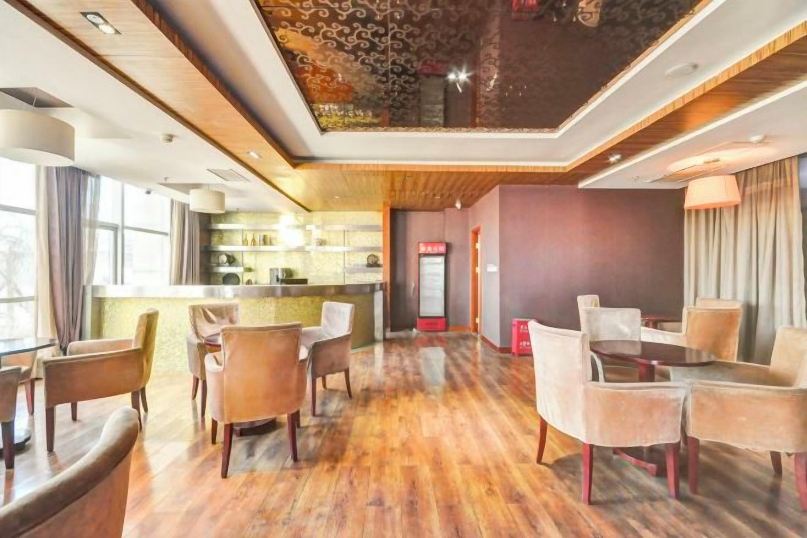 Un vestíbulo de hotel con una zona de bar, espacios de estar y una recepción.