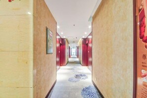 A hotel hallway with multiple doors, a patterned carpet, and framed signs on the walls. - Han Yue Hotel (Tangshan)