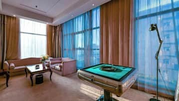 Un salón amplio con mesa de billar, sofá, mesa de centro y lámpara.
