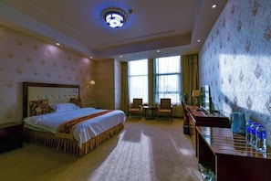 A hotel room with a large bed, a desk with a chair, a television, and a window with curtains. - Han Yue Hotel (Tangshan)
