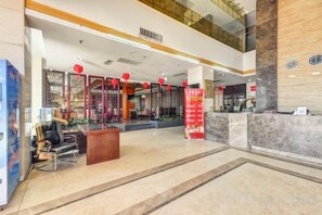 A hotel lobby with a reception desk, seating area, and decorative elements. - Han Yue Hotel (Tangshan)