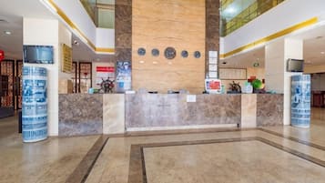 A hotel reception area with a marble counter, a wooden accent wall, and a modern design.