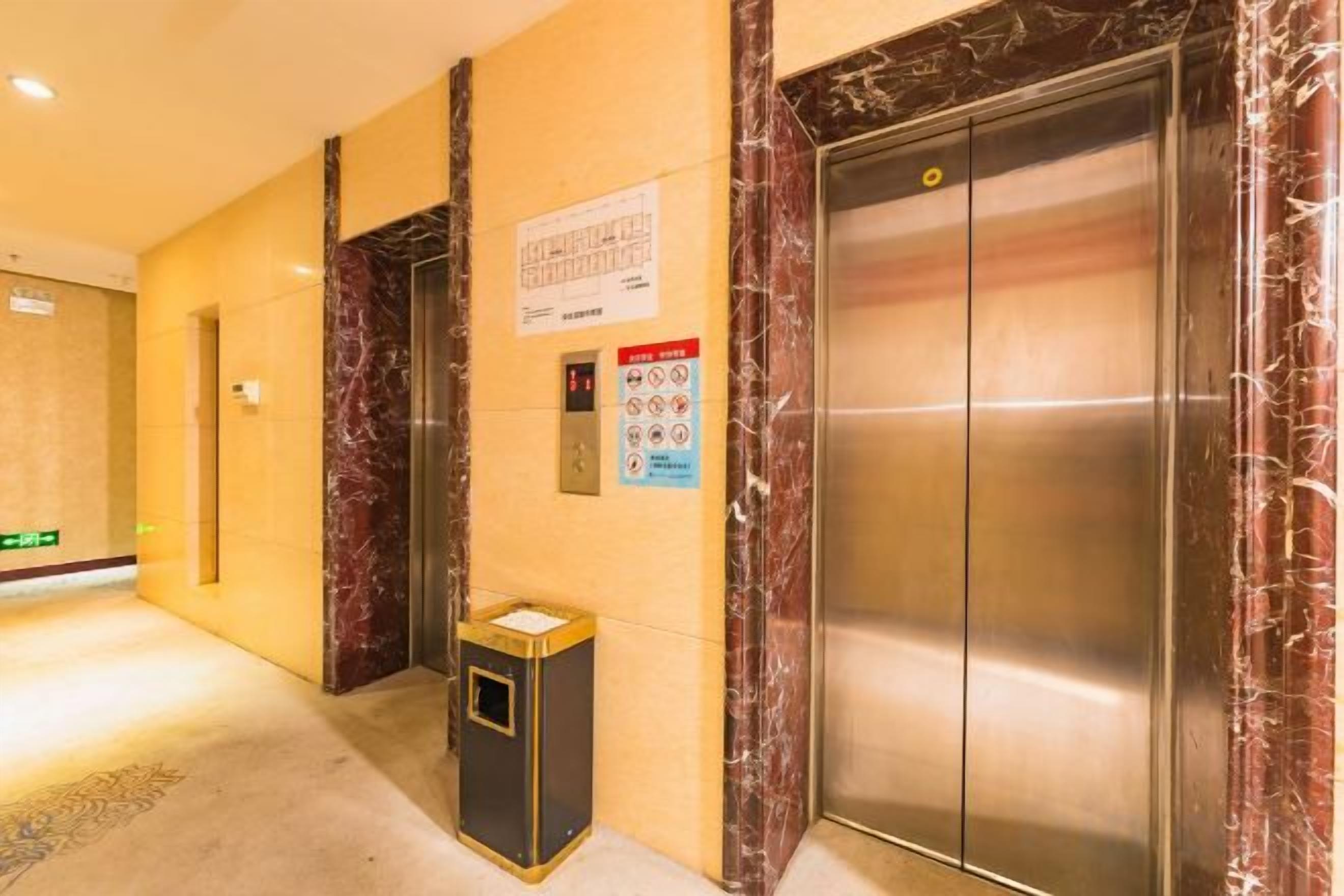 An elevator with a marble finish, a trash bin, and a sign with safety instructions.