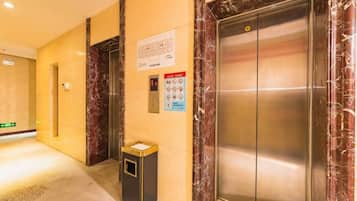 An elevator with a marble finish, a trash bin, and a sign with safety instructions.