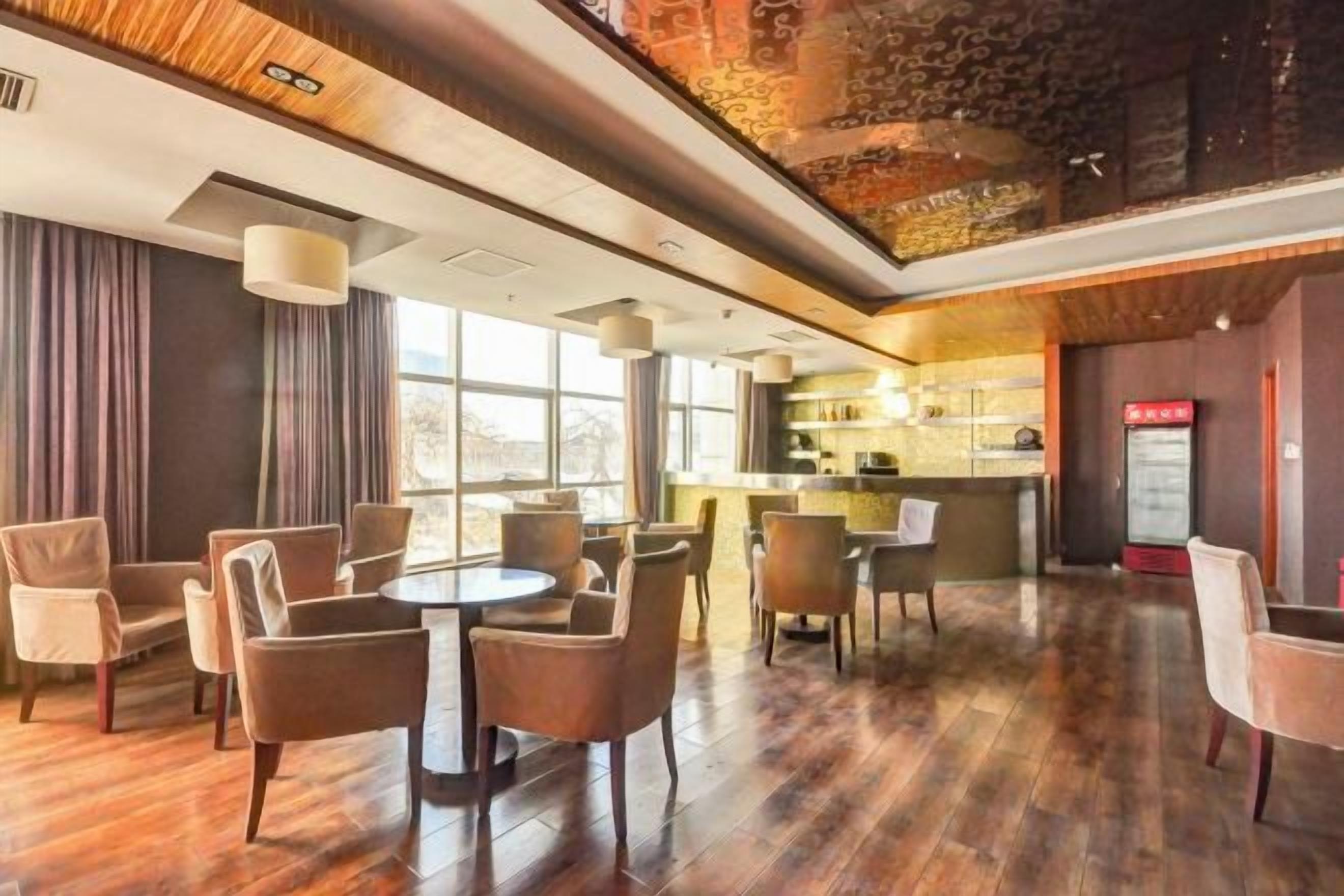 A hotel lobby with a bar area, seating arrangements, and a view of the outdoors.