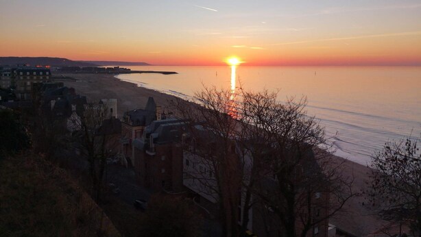 A sunset over a beach with buildings in the foreground.