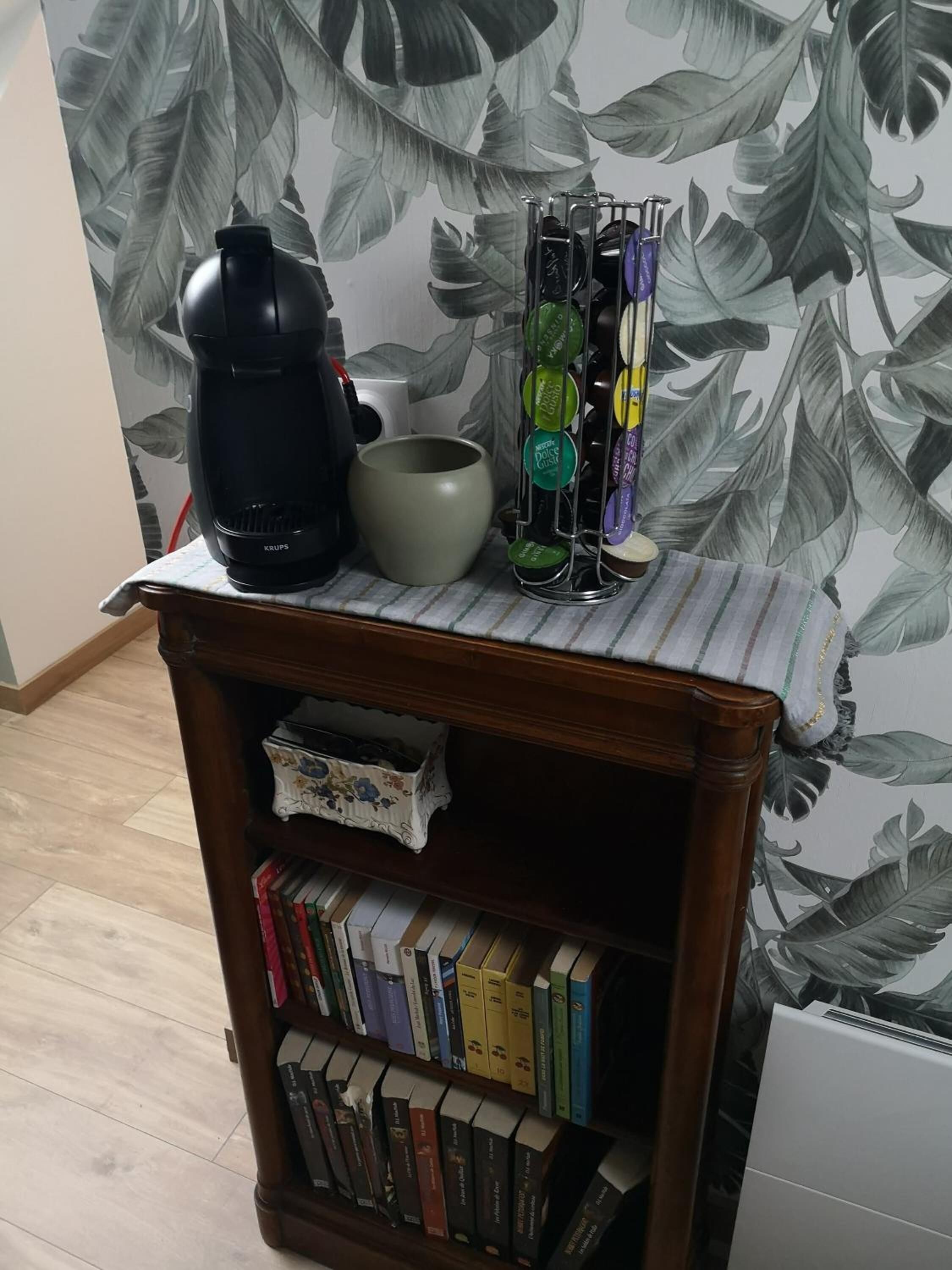 Une bibliothèque remplie de livres, une machine à café et une tasse.