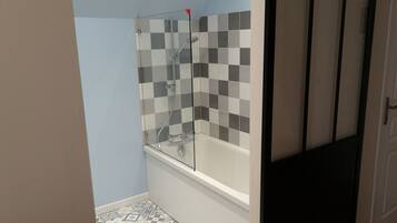 Een badkamer met een douche, een bad en een betegelde vloer.