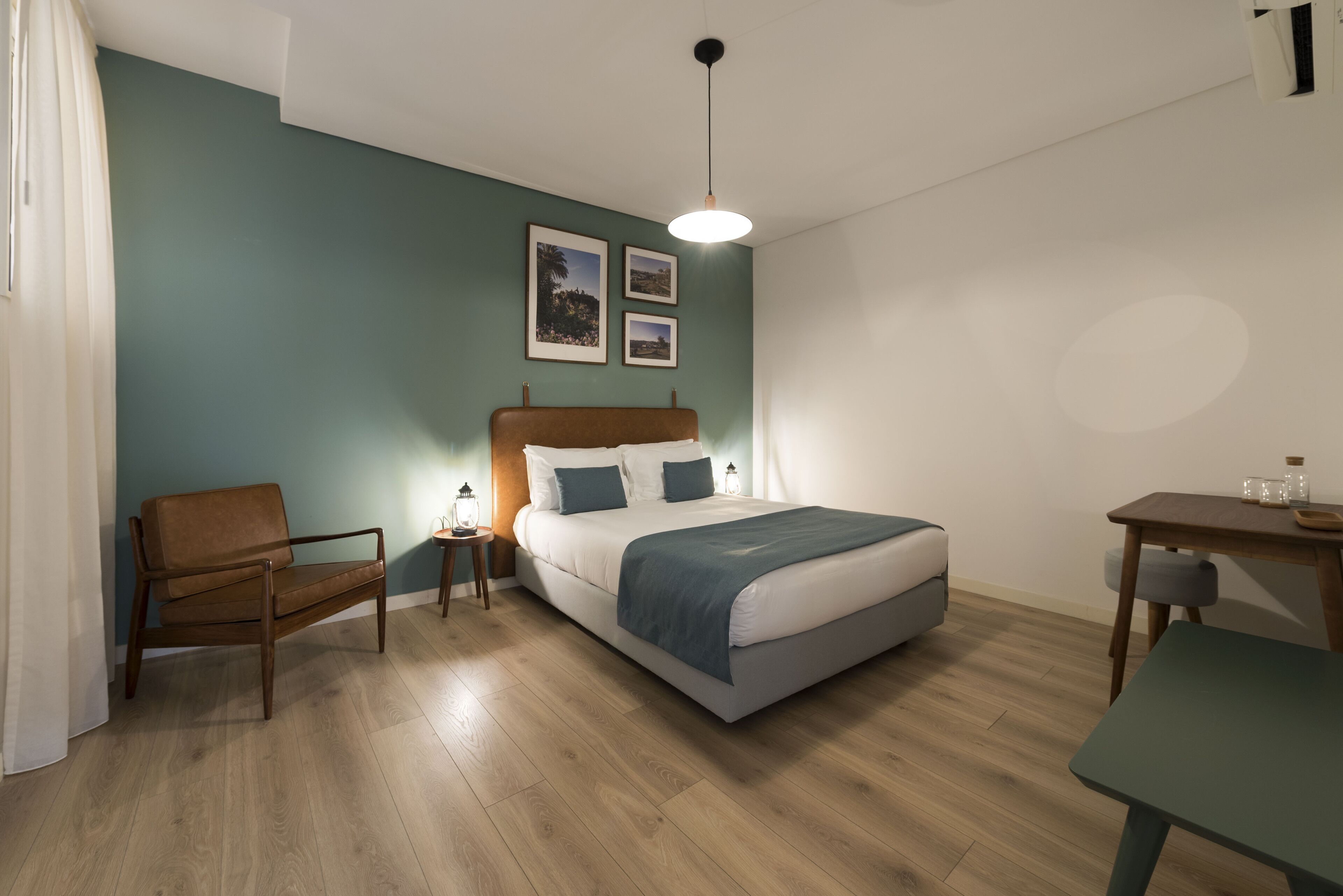 A modern bedroom with a bed, a chair, a small table, and a nightstand.