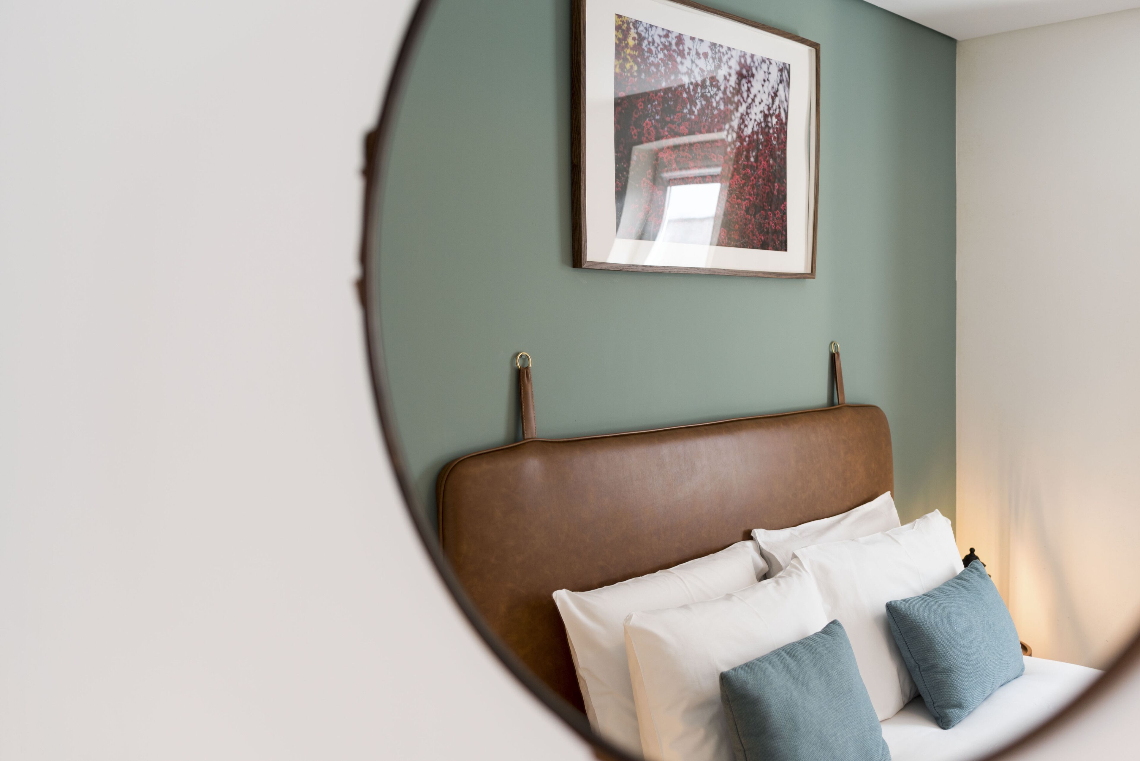 Une chambre à coucher avec une tête de lit marron, des oreillers blancs et bleus, et un tableau encadré accroché au mur.