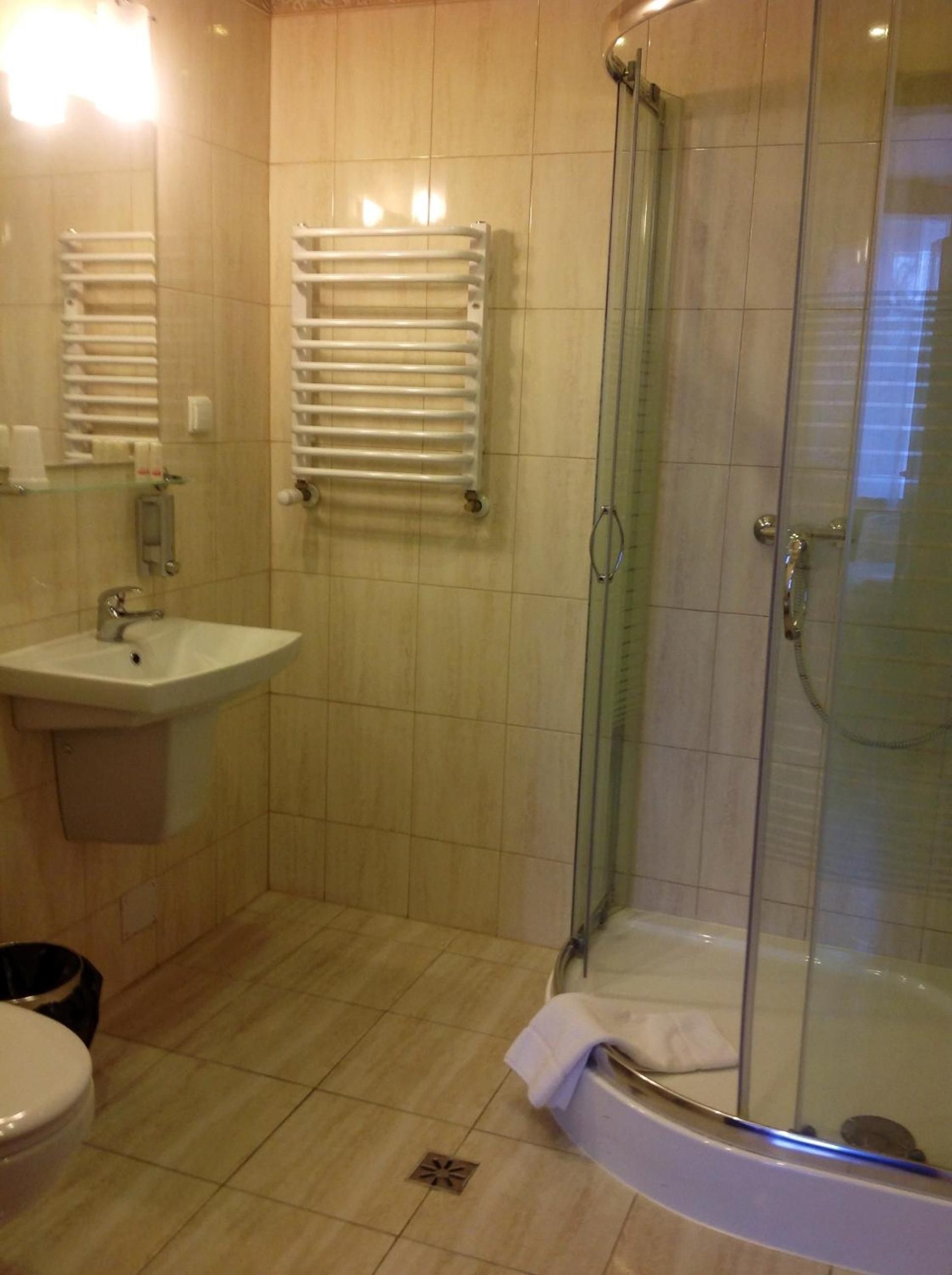 A bathroom with a sink, a glass-enclosed shower, and a towel rack.