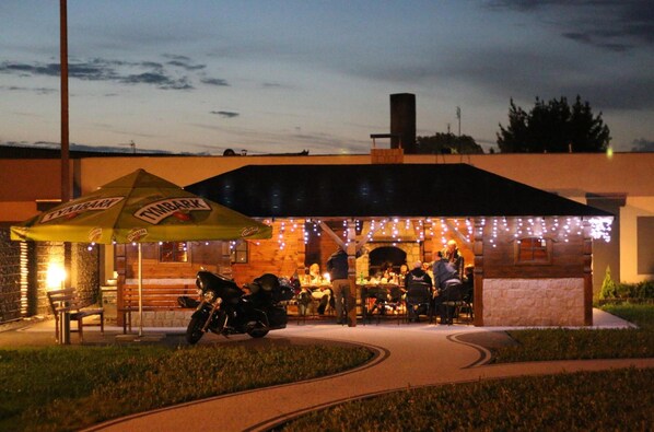 An outdoor restaurant with a covered patio, outdoor seating, and a motorcycle parked nearby.