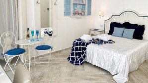 A bedroom with a bed, a desk with chairs, a mirror, and a wall with a decorative sign. - La Casa di Ada&Gigi Vacanze (Porto Cesareo)