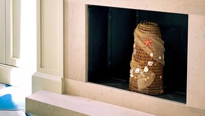 A fireplace with a woven basket decoration, a television above it, and a bookshelf with books and decorative items. - La Casa di Ada&Gigi Vacanze (Porto Cesareo)