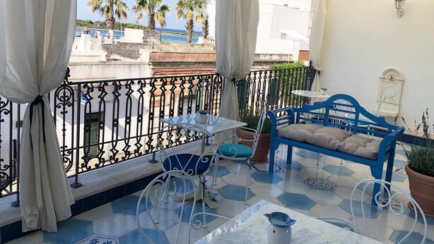 A balcony with a blue sofa, a small table, and a potted plant. - La Casa di Ada&Gigi Vacanze (Porto Cesareo)