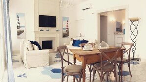 A dining area with a wooden table and chairs, a white sofa, and a fireplace. - La Casa di Ada&Gigi Vacanze (Porto Cesareo)