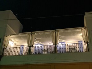 Ein Balkon mit weißen Vorhängen und einem Metallgeländer.