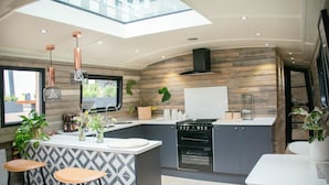 A modern kitchen with a central island, stainless steel appliances, and a skylight. - The Boathouse London (London)