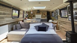 A cozy cabin interior with a bed, sofa, and a small kitchen area. - The Boathouse London (London)