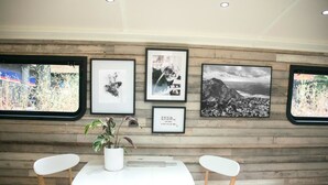 A room with a wooden wall, a white table, and four white chairs. There are framed pictures on the wall. - The Boathouse London (London)