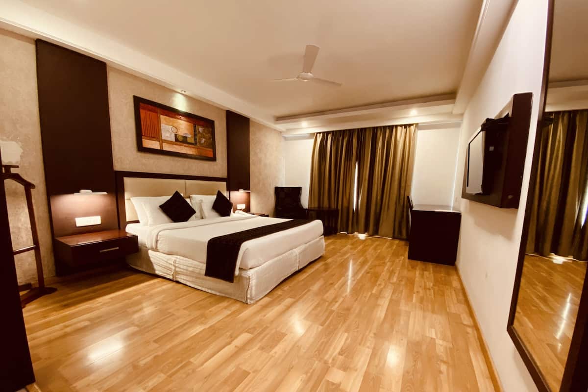 A hotel room with a large bed, a nightstand, a ceiling fan, and a painting on the wall.