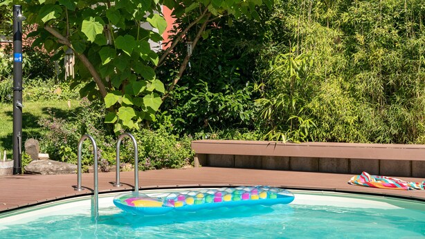 A swimming pool with a colorful inflatable raft, a metal ladder, and a bench. - Entspannen im Taunus (Taunusstein)