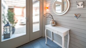 Ein Zimmer mit einer weißen Kommode, einem runden Spiegel und einer Vase mit Zweigen.
