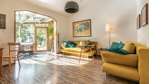 Ein modernes Wohnzimmer mit einem gelben Sofa, Holzboden und einem großen Fenster, das natürliches Licht hereinlässt.