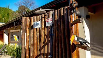 A wooden fence with signs, a birdhouse, and a bird perched on a branch.