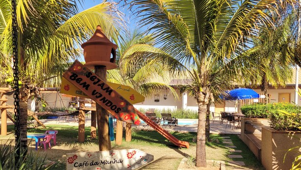 Un resort tropical con palmeras, un tobogán y señales que indican la ubicación de servicios como un café y bar.