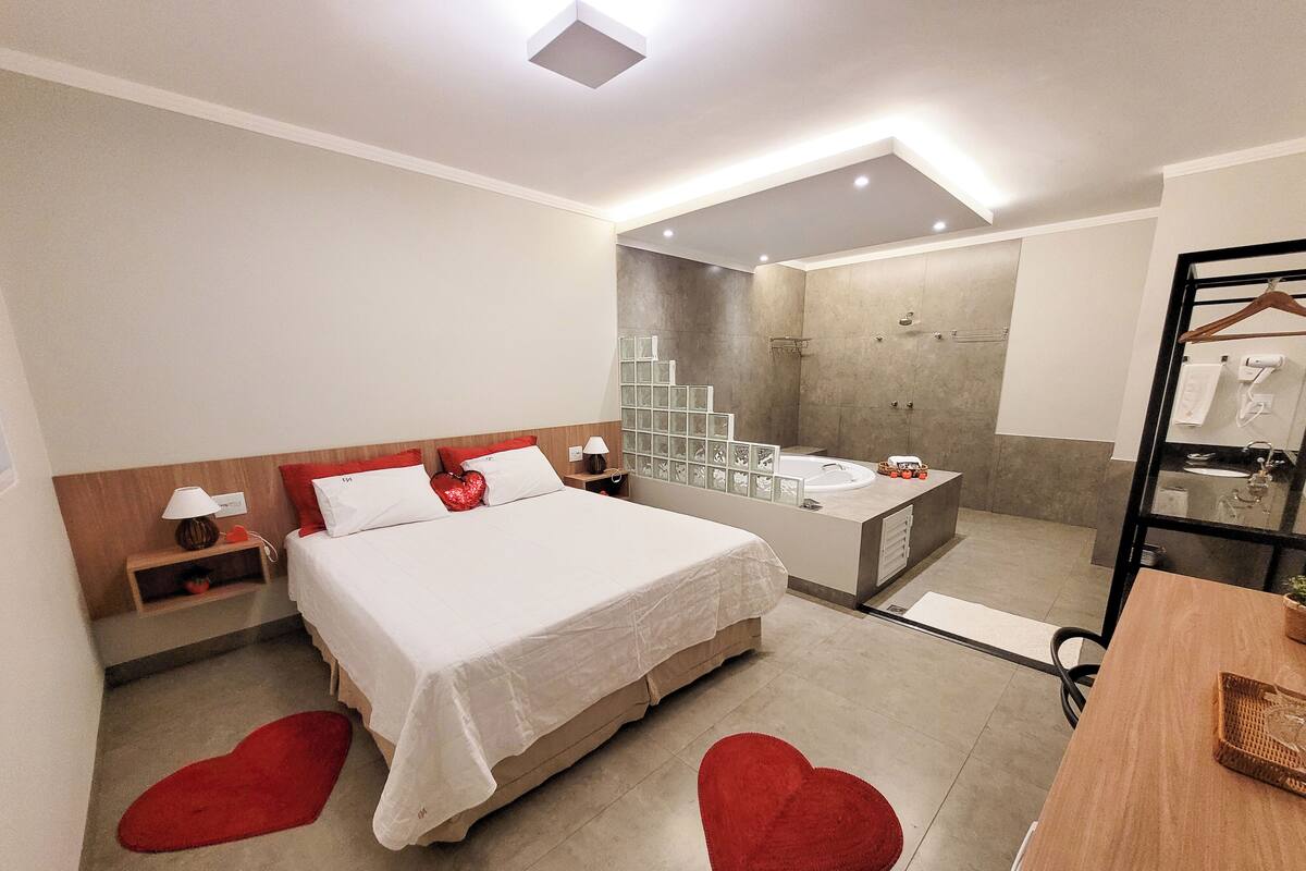 A modern hotel room with a large bed, a separate bathroom with a bathtub, and a shower.