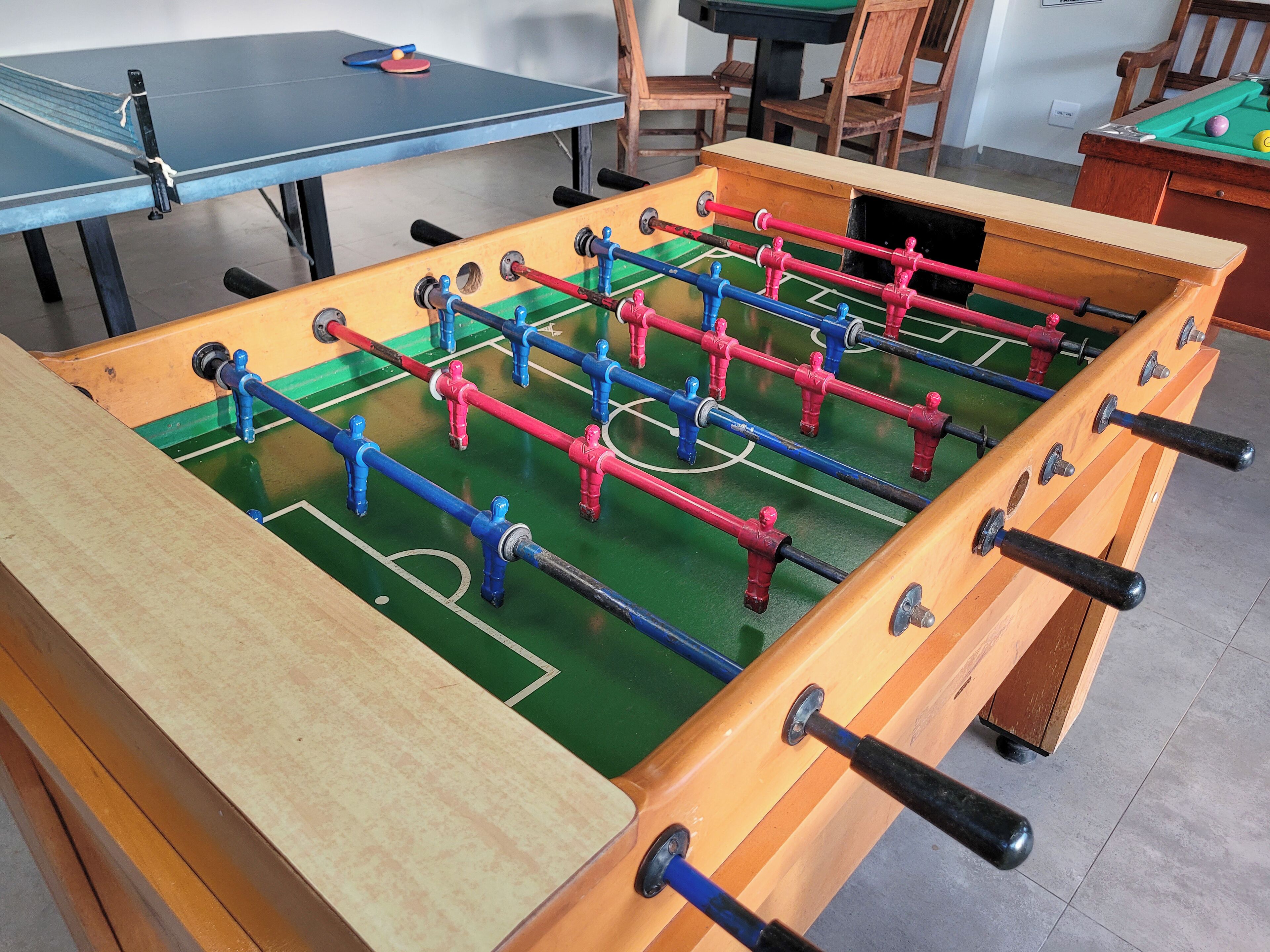 A foosball table with a wooden frame and a green playing surface.