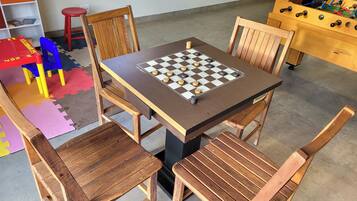 Una mesa de madera con un tablero de juego de cuadros, rodeada de sillas de madera.