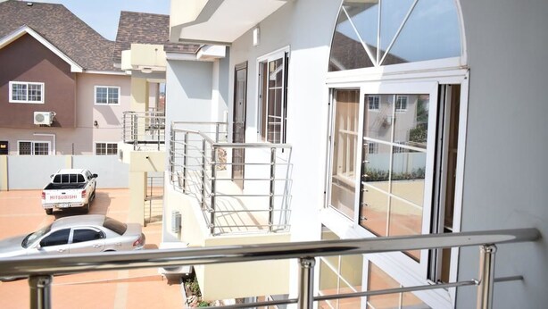 A residential building with a balcony, a Mitsubishi car, and a Mitsubishi van parked in the driveway. - Relle Suites Hotel (Accra)