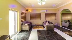 A spacious living area with two sofas, a coffee table, and a patterned rug. - Relle Suites Hotel (Accra)