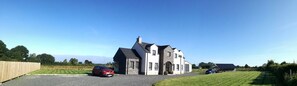 A two-story house with a stone facade, a driveway, and a lawn. - Boutique Country House BandB (Crumlin)