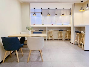 A modern dining area with a long table, several chairs, and bar stools.