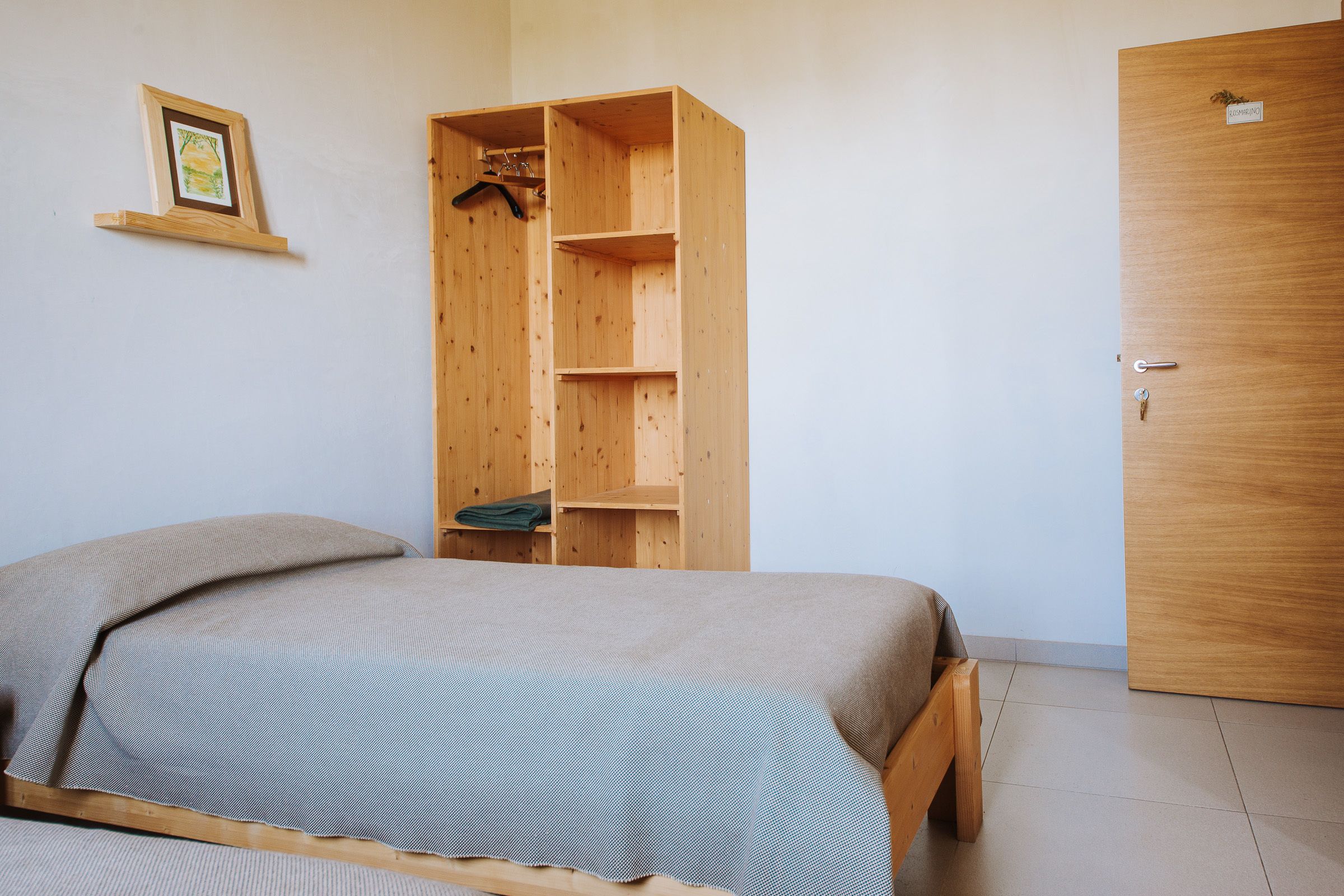 Un dormitorio con una cama, un armario de madera y una puerta.