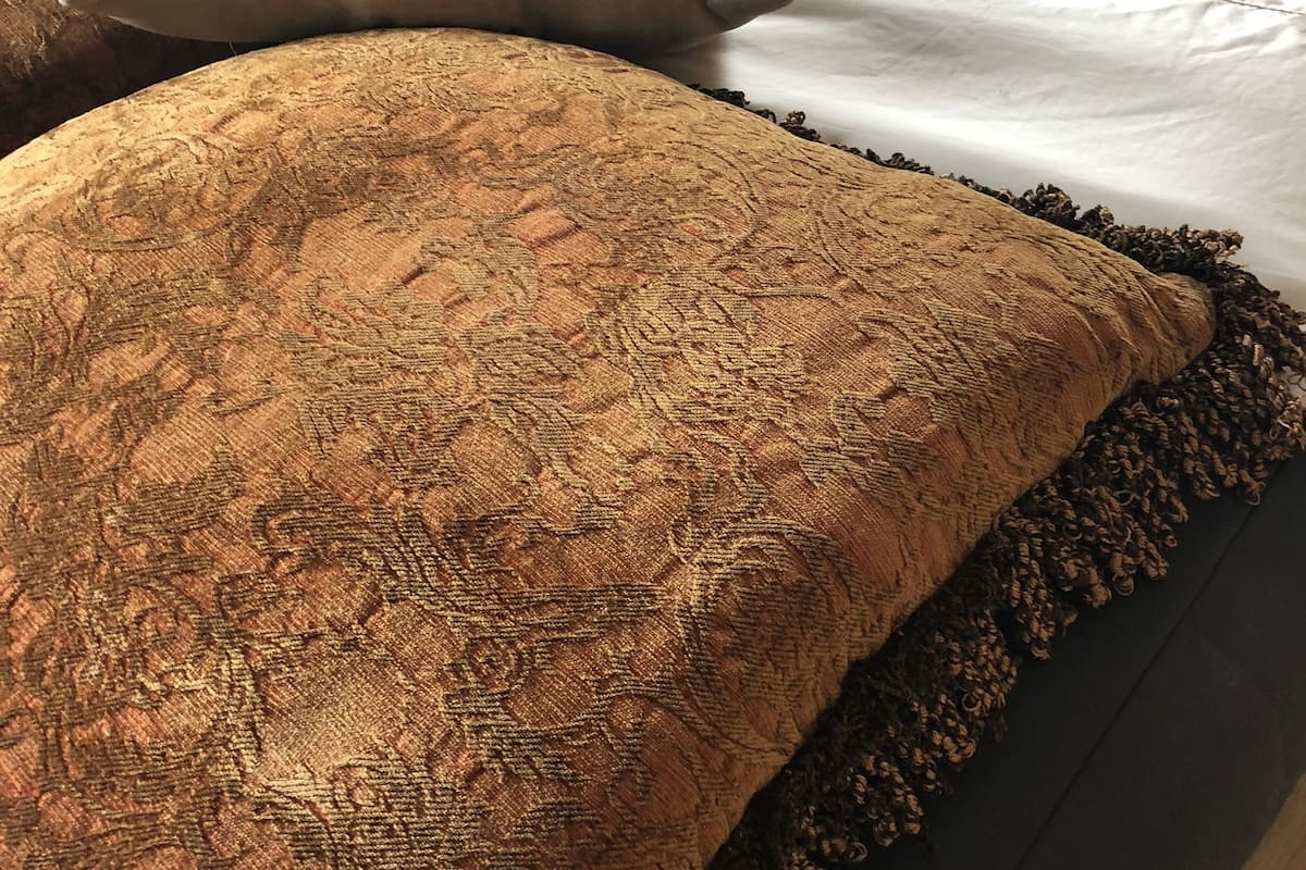 Ein Bett mit einer weißen Matratze und zwei Kissen, eines weiß und eines gemustert.