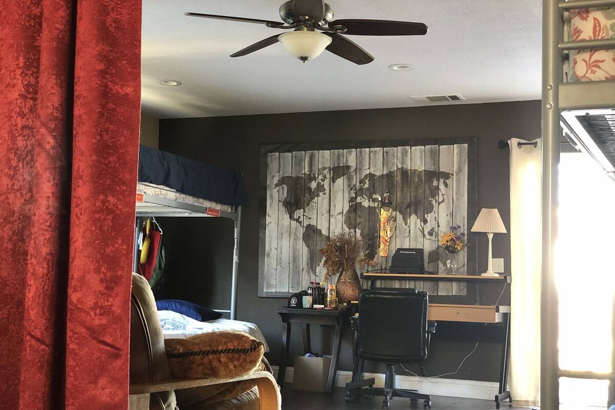 Ein Zimmer mit Bett, Schreibtisch, Stuhl und Deckenventilator.