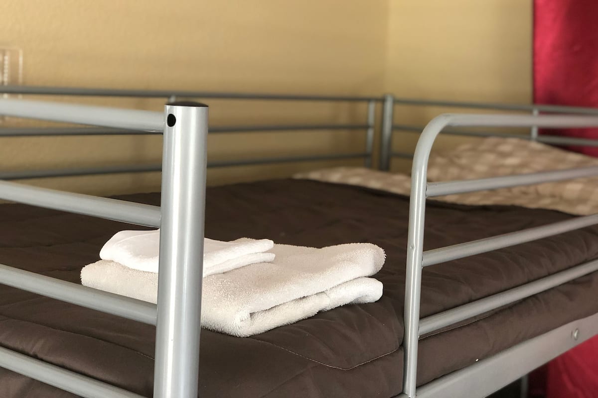Ein Etagenbett mit Metallgestell, einer braunen Matratze und zwei weißen Handtüchern.