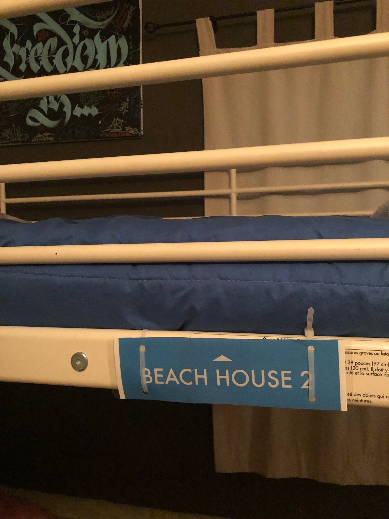 A bunk bed with a blue mattress labeled "BEACH HOUSE 2".