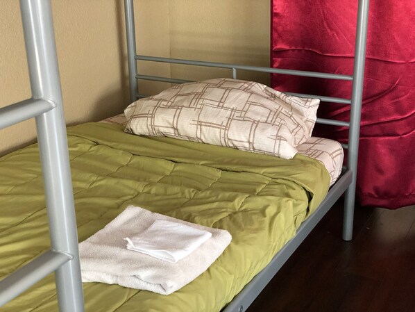 A bunk bed with a green bedspread and a white towel on the lower bunk.