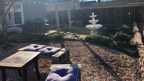 A backyard with a wooden pergola, a stone fountain, and outdoor seating. - WHOLE Family - WholeStyl - Hostel (Sacramento)