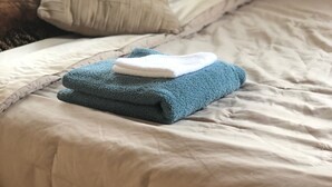 A bed with a beige duvet, two pillows, and a folded blue towel. - WHOLE Family - WholeStyl - Hostel (Sacramento)