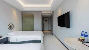 Habitación de hotel con dos camas, un televisor de pantalla plana, una mesita de noche con botellas de agua y un diseño moderno.