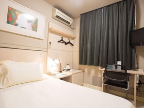 A hotel room with a bed, a desk, a chair, a TV, an air conditioner, and a window with curtains. - JIN Jiang INN Pingan Street (Shijiazhuang)