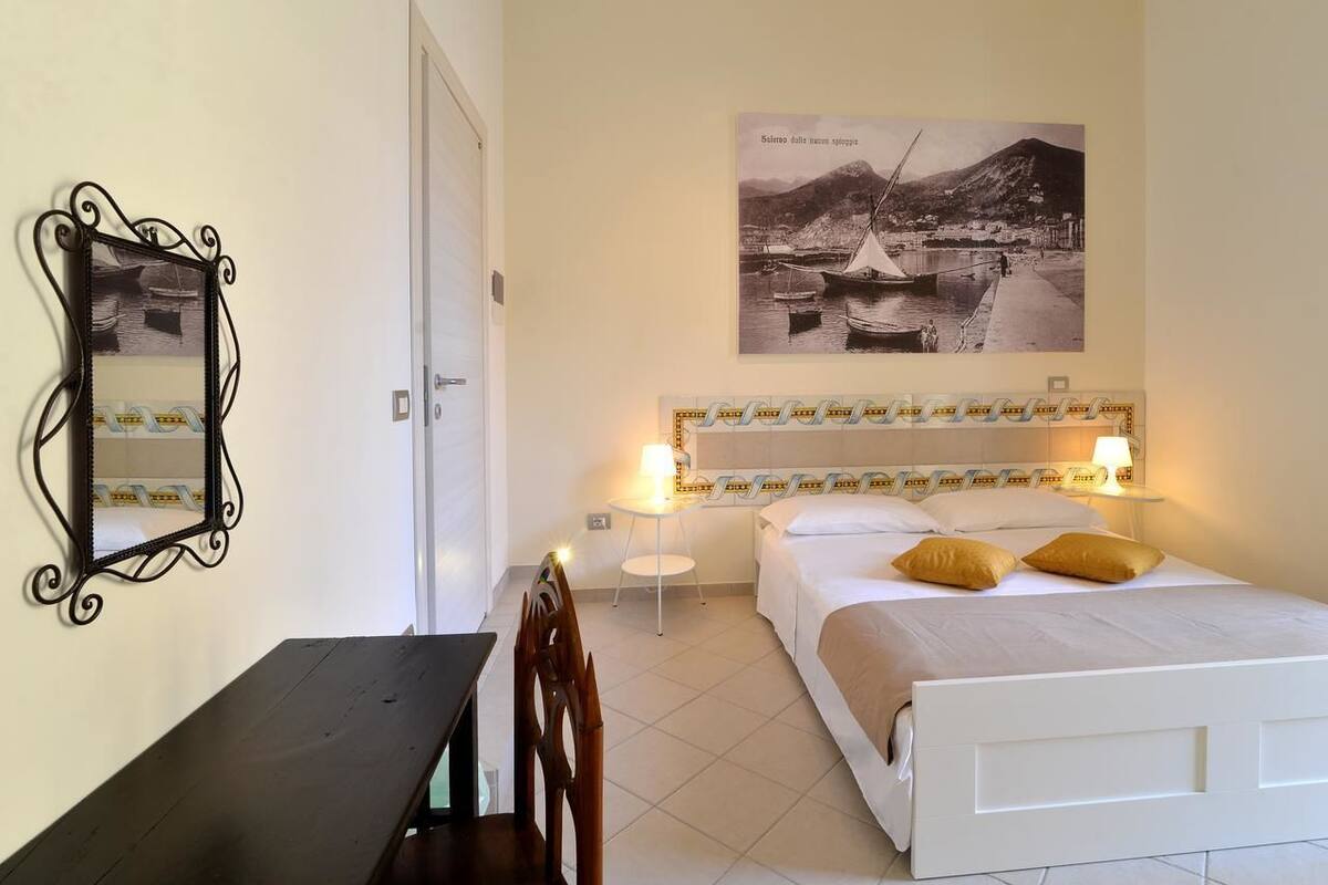 A hotel room with a bed, bedside lamps, a desk, and a chair.